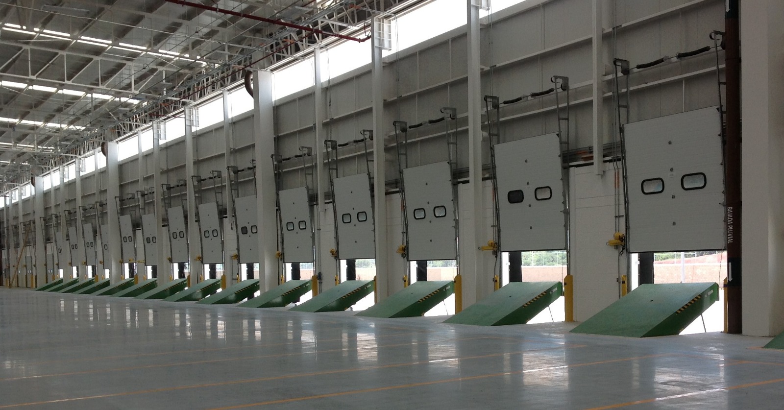 Línea de andenes con rampas niveladoras verdes en centro logístico