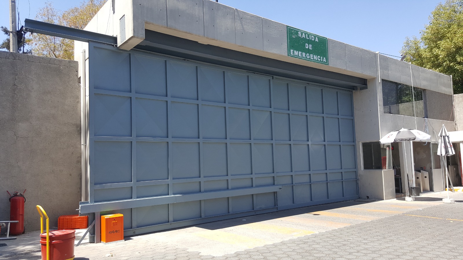 Portón corredizo automático de gran claro con operador FAAC en salida de emergencia